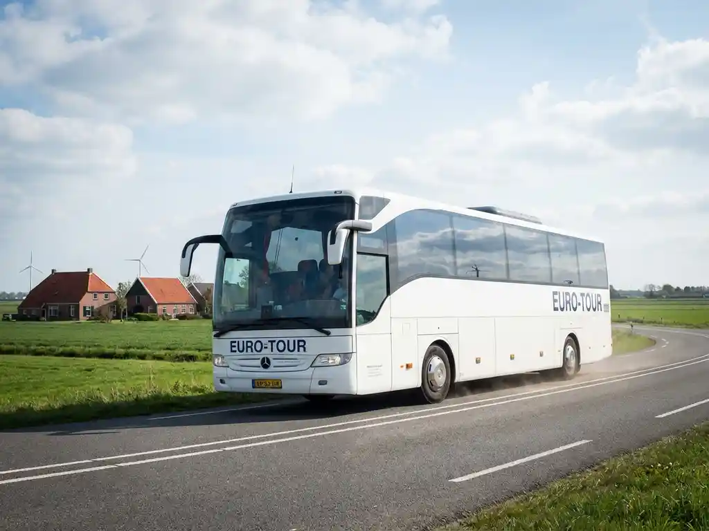 Witte touringcar rijdt over Nederlandse snelweg met traditionele boerderijen en groene polders op de achtergrond