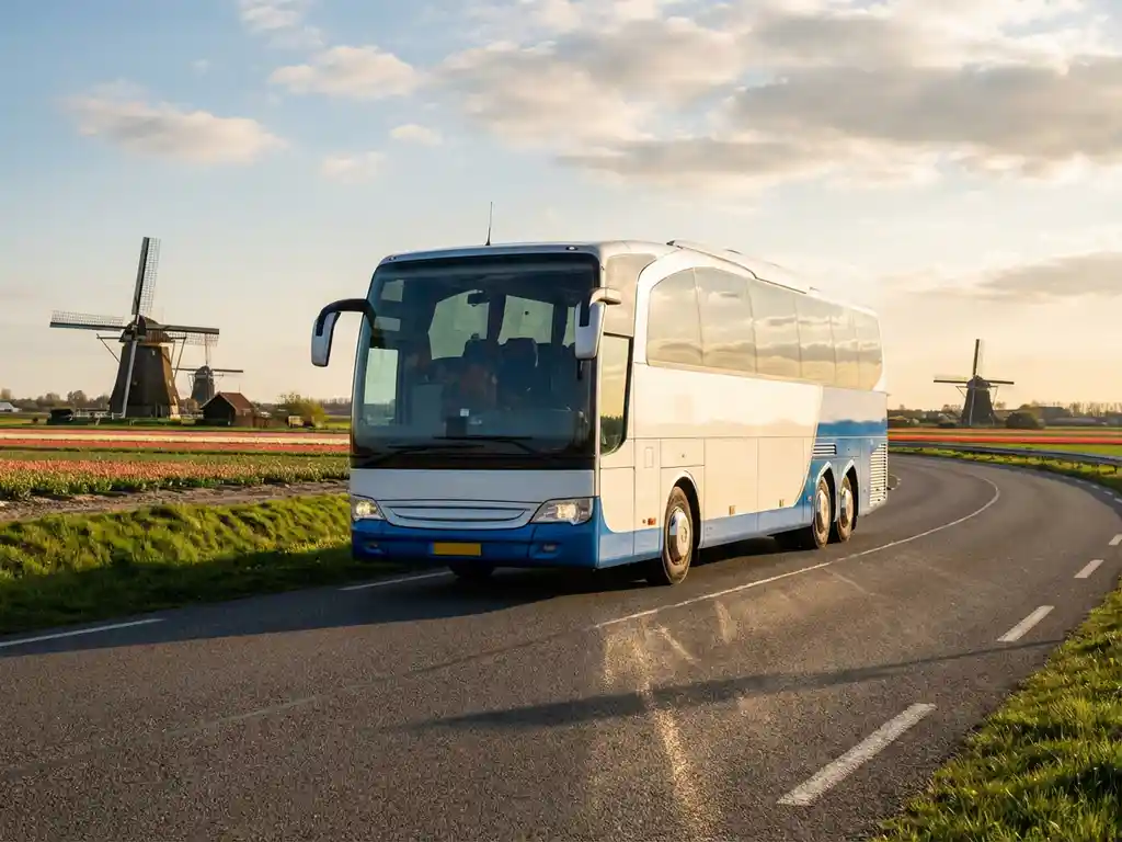 Moderne touringcar rijdt over Nederlandse snelweg met windmolens en tulpenvelden op de achtergrond