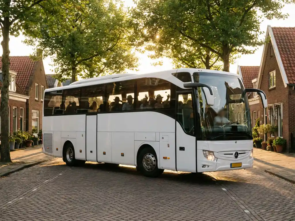 Witte touringcar rijdt over kinderkopjes door Nederlands dorp met bakstenen huizen en rode pannendaken