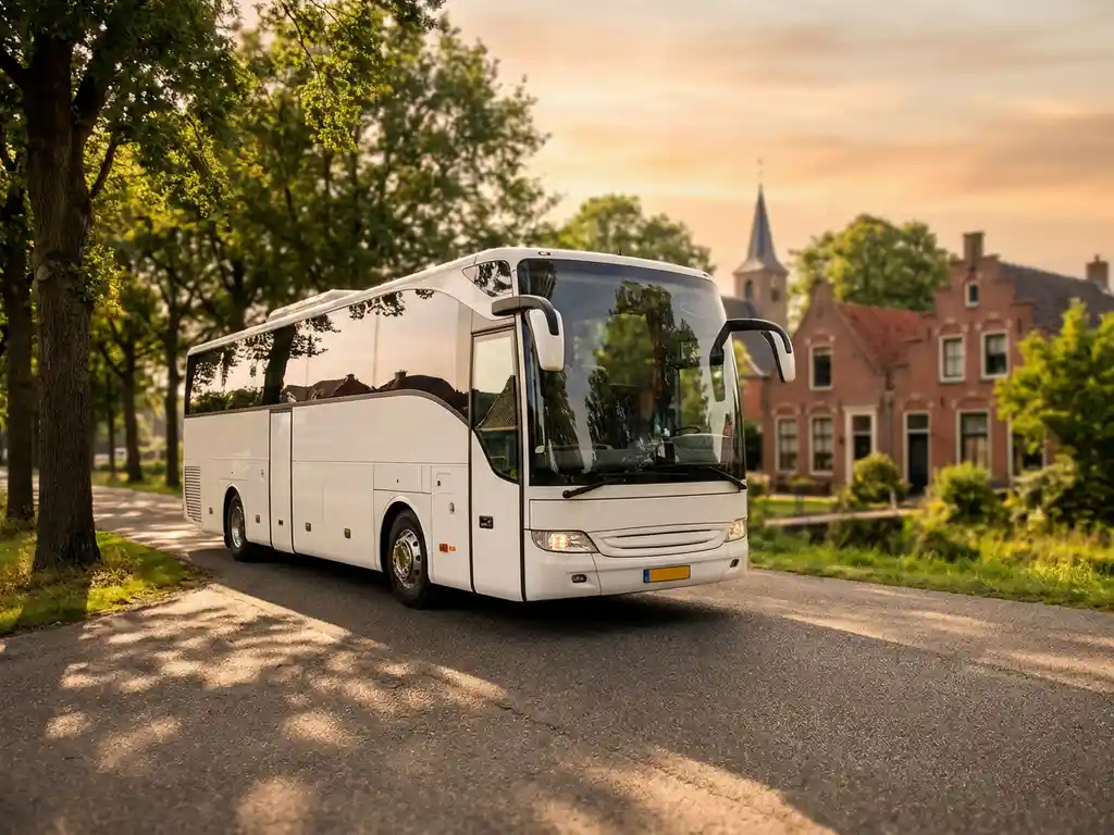 Witte touringcar met panoramaramen rijdt door pittoresk Nederlands dorp met bakstenen huizen en kerktoren