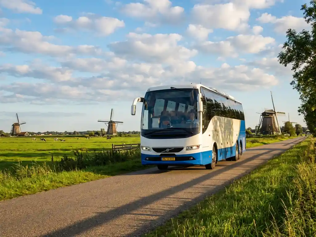 Moderne touringcar rijdt door Nederlands landschap met traditionele windmolens en groene polders op de achtergrond