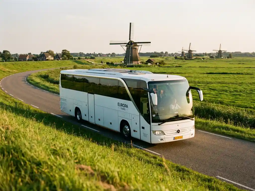 Witte touringcar rijdt door Nederlands landschap met molens en groene polders in gouden middaglicht