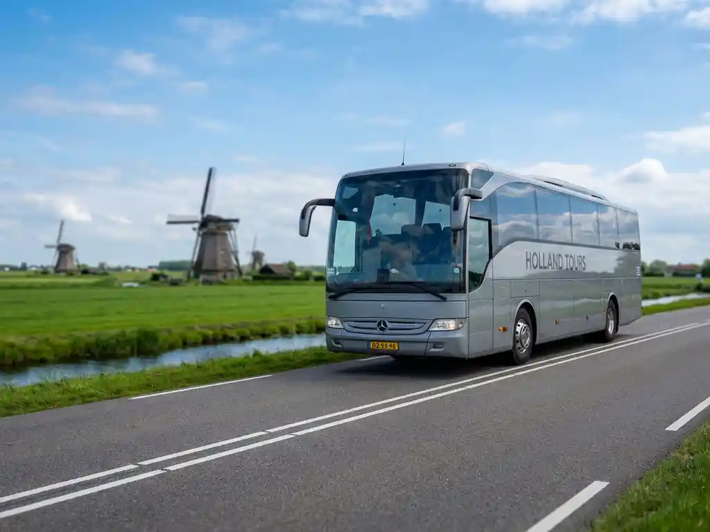 Moderne touringcar rijdt door Nederlands platteland met traditionele windmolens en groene polders op achtergrond
