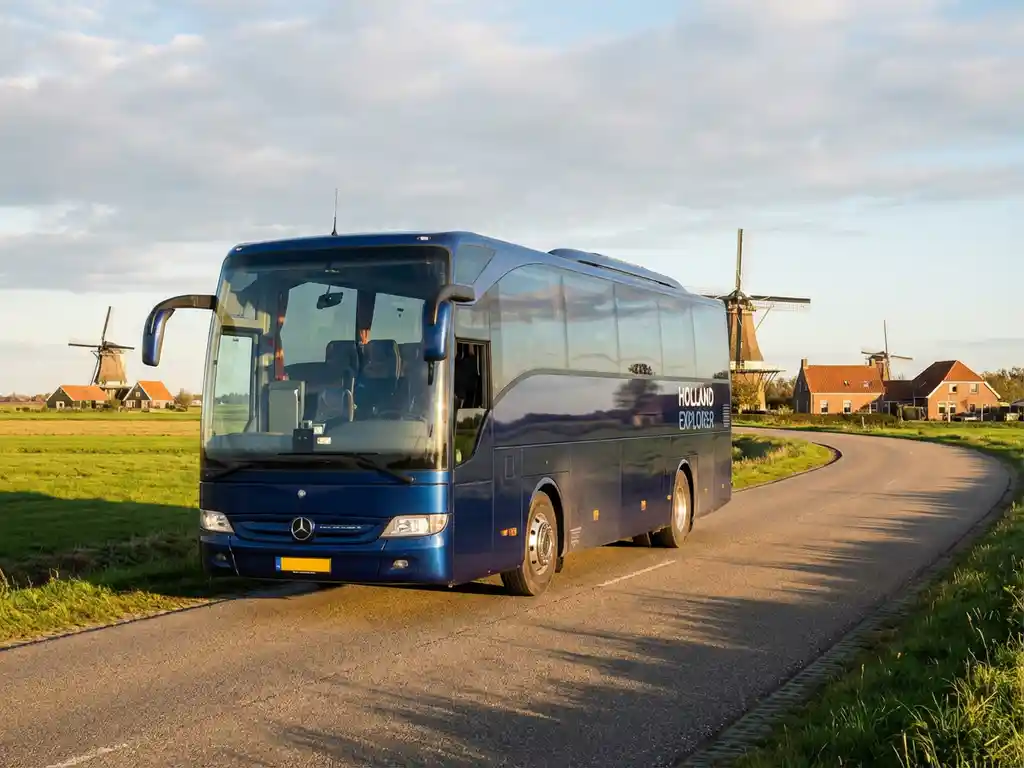 Grote touringcar rijdt door Nederlands landschap met traditionele windmolens en groene velden in gouden middaglicht