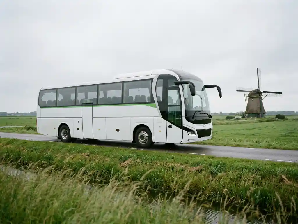 Elektrische touringcar voor 50 passagiers op een Nederlandse polderwegen met groene weiden en een windmolen op de achtergrond.