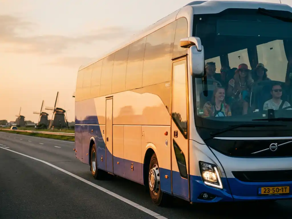 Touringcar met festivalgangers op Nederlandse snelweg, omgeven door polders en windmolens in warm gouden avondlicht.