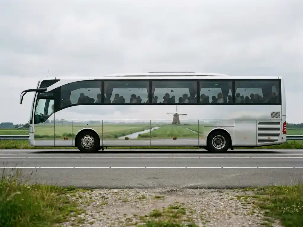 Moderne touringcar rijdt over Nederlandse snelweg met polders en windmolen zichtbaar op de achtergrond.