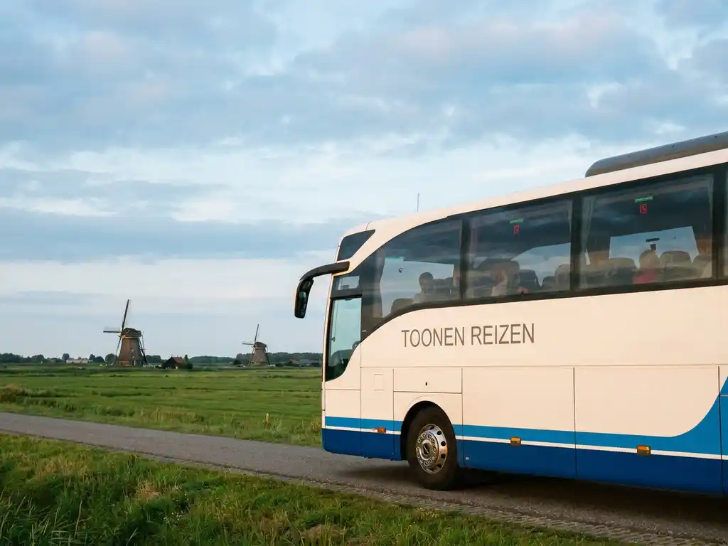 Toonen Reizen touringcar rijdt langs een typisch Hollands polderpad met windmolens en groene weilanden in middagzon.
