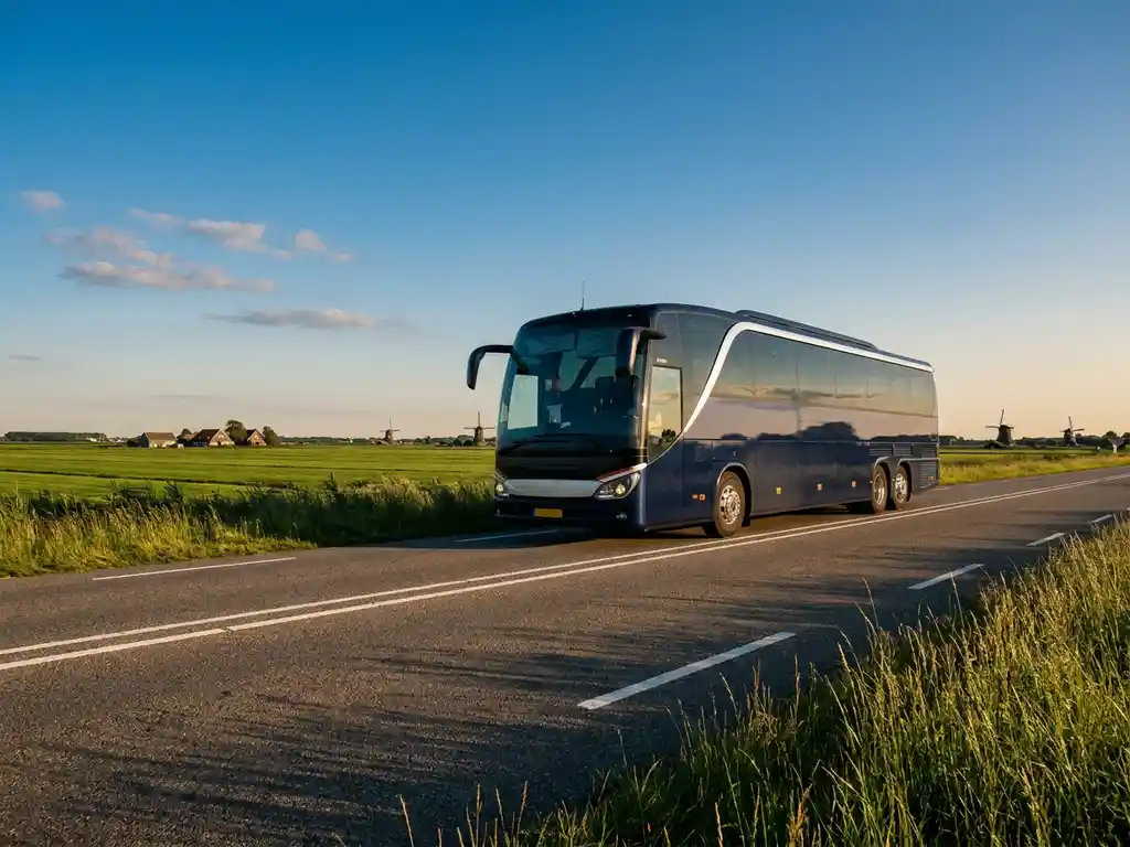 Touringcar rijdt over Nederlandse snelweg door vlak polderlandschap met windmolens aan de horizon in warm middaglicht.